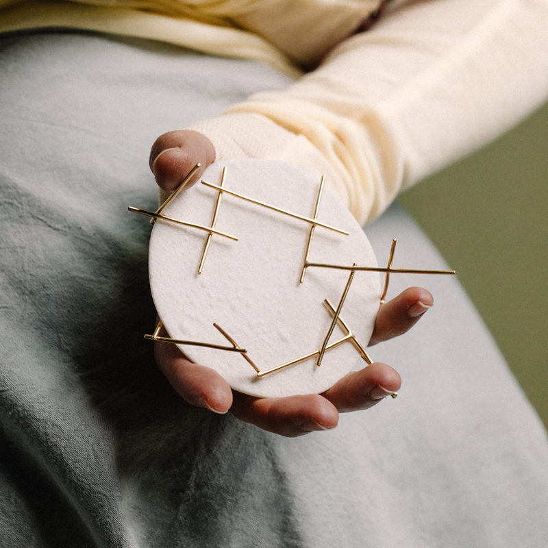 imagen detalle de broche en la mano, porcelana y latón chapado en oro, joyería contemporánea.